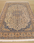 Louie Traditional Ivory Hand Knotted Wool & Silk Rug, intricately patterned in muted ivory tones, lending timeless elegance to a warmly lit room setting.