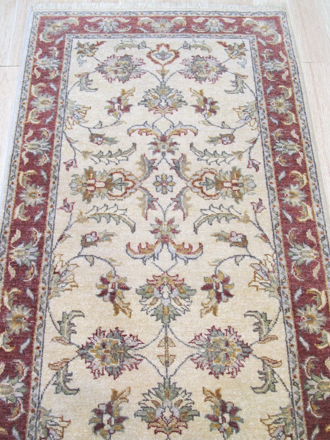 Beautiful Maya Ivory Hand Knotted Wool Rug, showcasing its soft, ivory hues and intricate hand-knotted detailing, rests on a light hardwood floor, offering a serene and elegant touch to the room's decor.