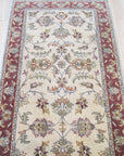Beautiful Maya Ivory Hand Knotted Wool Rug, showcasing its soft, ivory hues and intricate hand-knotted detailing, rests on a light hardwood floor, offering a serene and elegant touch to the room's decor.