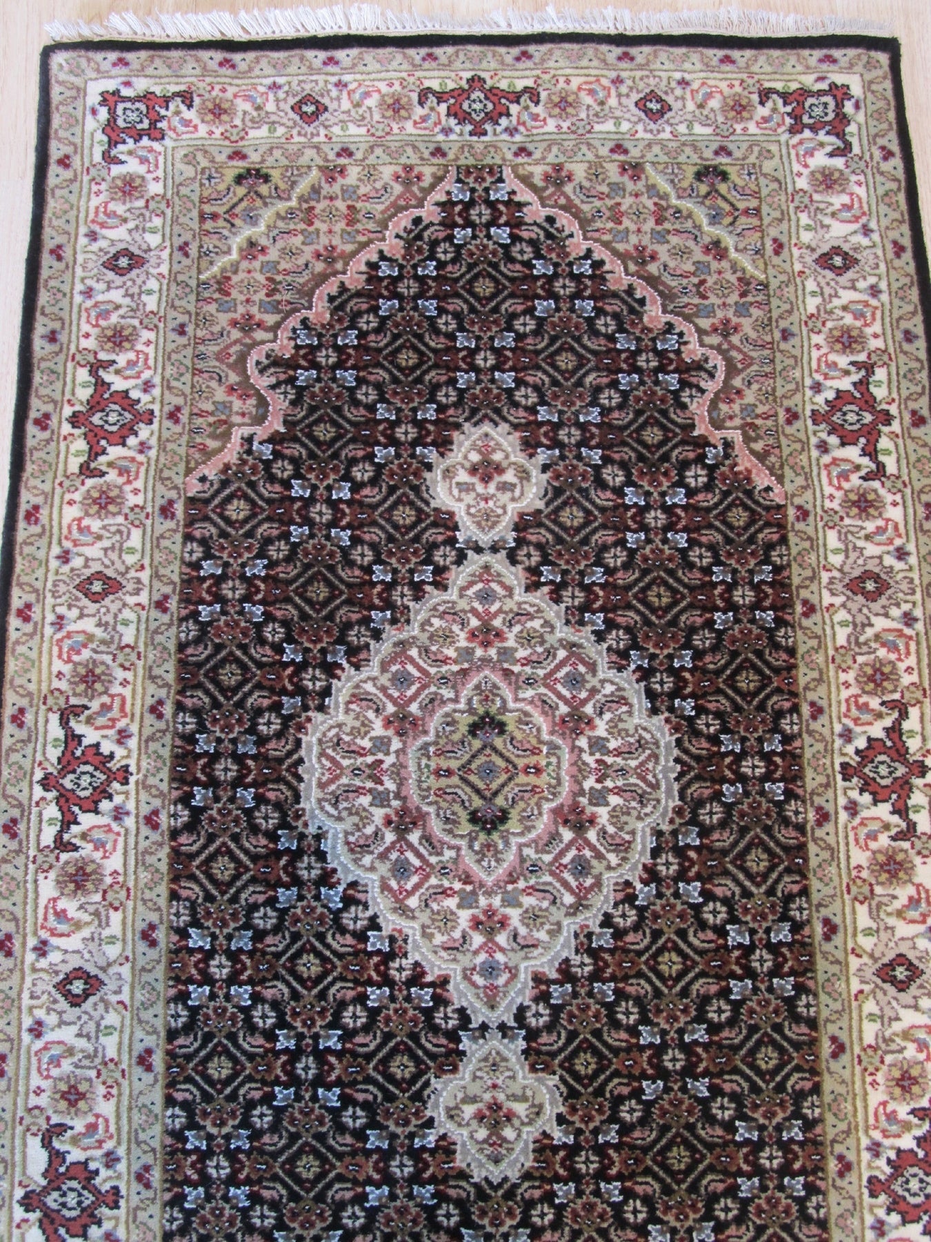 Ophelia Amara Brown Hand Knotted Wool Rug, showcasing intricate geometric patterns in warm brown tones, lies flat on a light wooden floor, its soft texture inviting touch in a bright, airy living space.