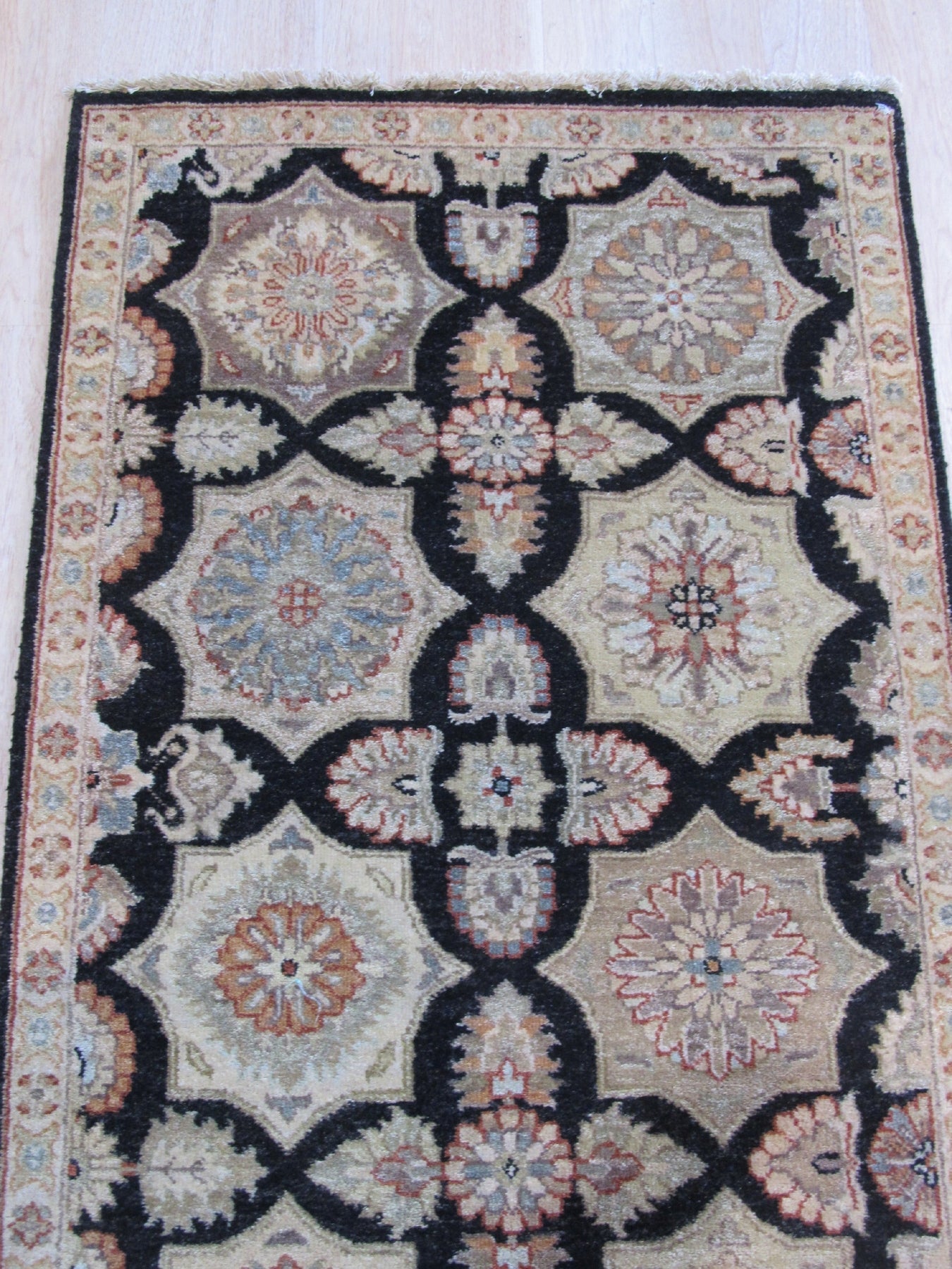 Timeless Agra Black Hand Knotted Wool Rug, showcasing a detailed geometric pattern with subtle variations in black and grey tones, displayed in a bright, modern living room setting.