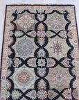 Timeless Agra Black Hand Knotted Wool Rug, showcasing a detailed geometric pattern with subtle variations in black and grey tones, displayed in a bright, modern living room setting.
