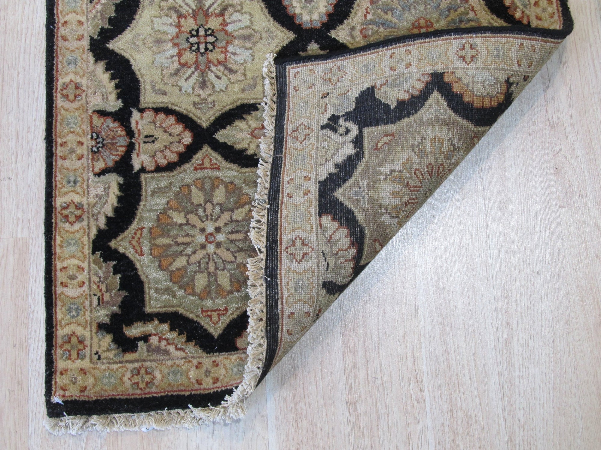 Timeless Agra Black Hand Knotted Wool Rug, richly detailed with intricate patterns, anchors a living room vignette with a modern sofa and textured pillows.