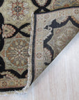 Timeless Agra Black Hand Knotted Wool Rug, richly detailed with intricate patterns, anchors a living room vignette with a modern sofa and textured pillows.