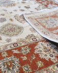Exquisite Agra Multicolor Hand Knotted Wool Rug, its vibrant reds, blues, greens, and golds creating an intricate floral pattern, resting on a light hardwood floor, adding warmth and texture to the room.