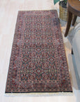 Sleek Oriental Navy Hand Knotted Wool Rug, its intricate pattern unfolding across a deep navy field, hand-knotted wool adding texture to the refined design, displayed in a room setting.