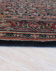 Sleek Oriental Navy Hand Knotted Wool Rug, its deep navy field detailed with traditional patterns in lighter hues, lies anchored in a warmly lit room; hardwood floors and neutral walls create a sophisticated backdrop for the luxurious wool texture.
