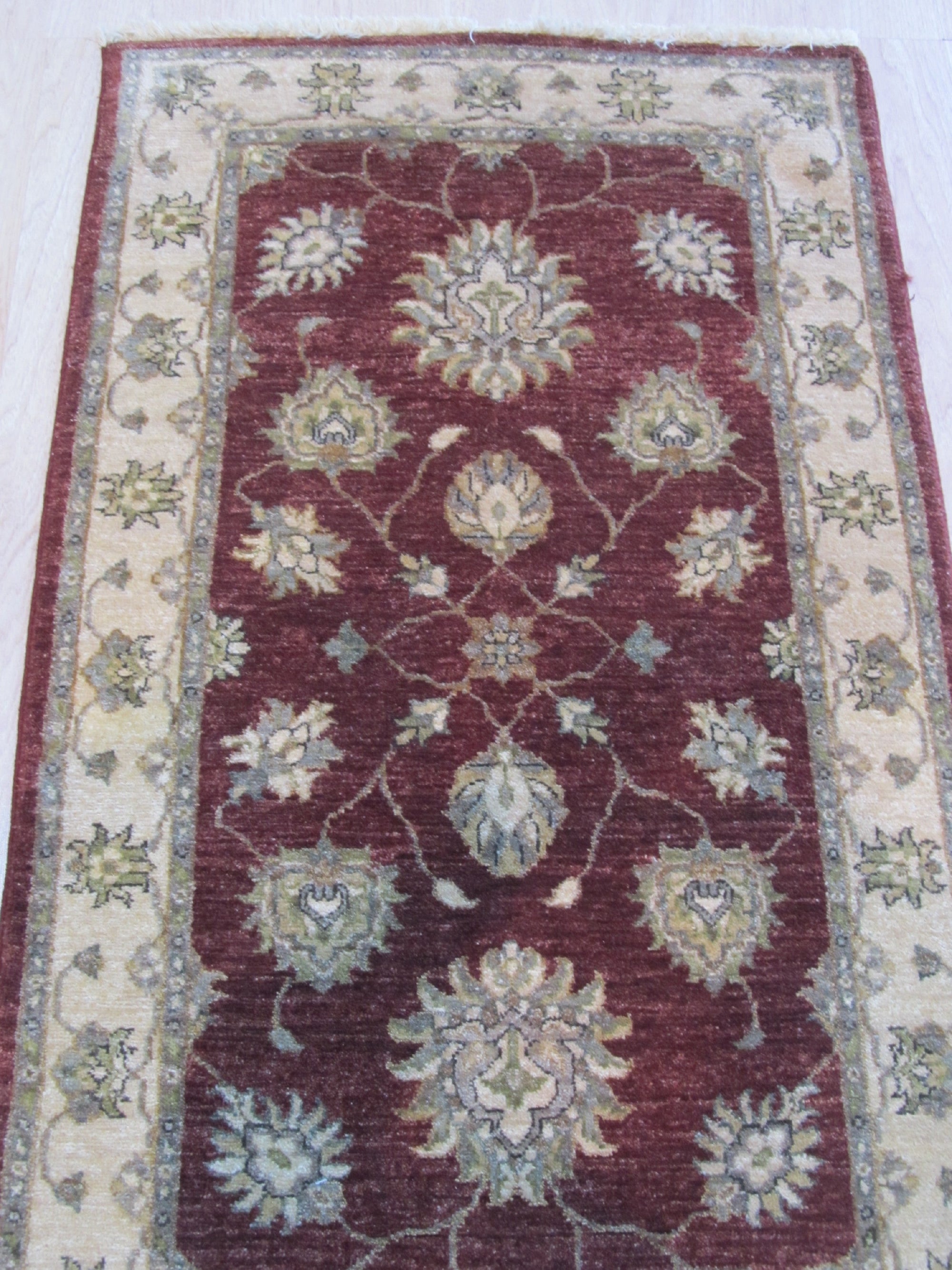 Timeless Oushak Red Hand Knotted Wool Rug, its intricate floral and geometric patterns rendered in rich reds and creams, lies gracefully on a light hardwood floor, suggesting warmth and elegance within a living space.