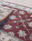 Timeless Oushak Red Hand Knotted Wool Rug, richly detailed with a traditional Oushak pattern in vibrant reds and muted creams, lies elegantly on a polished hardwood floor.