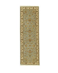 Zinnia Agra Green Hand Knotted Wool Rug, seen in a living room setting, features a lush green field and intricate, traditional Agra-style floral motifs. Hand-knotted wool construction offers luxurious texture and enduring quality.