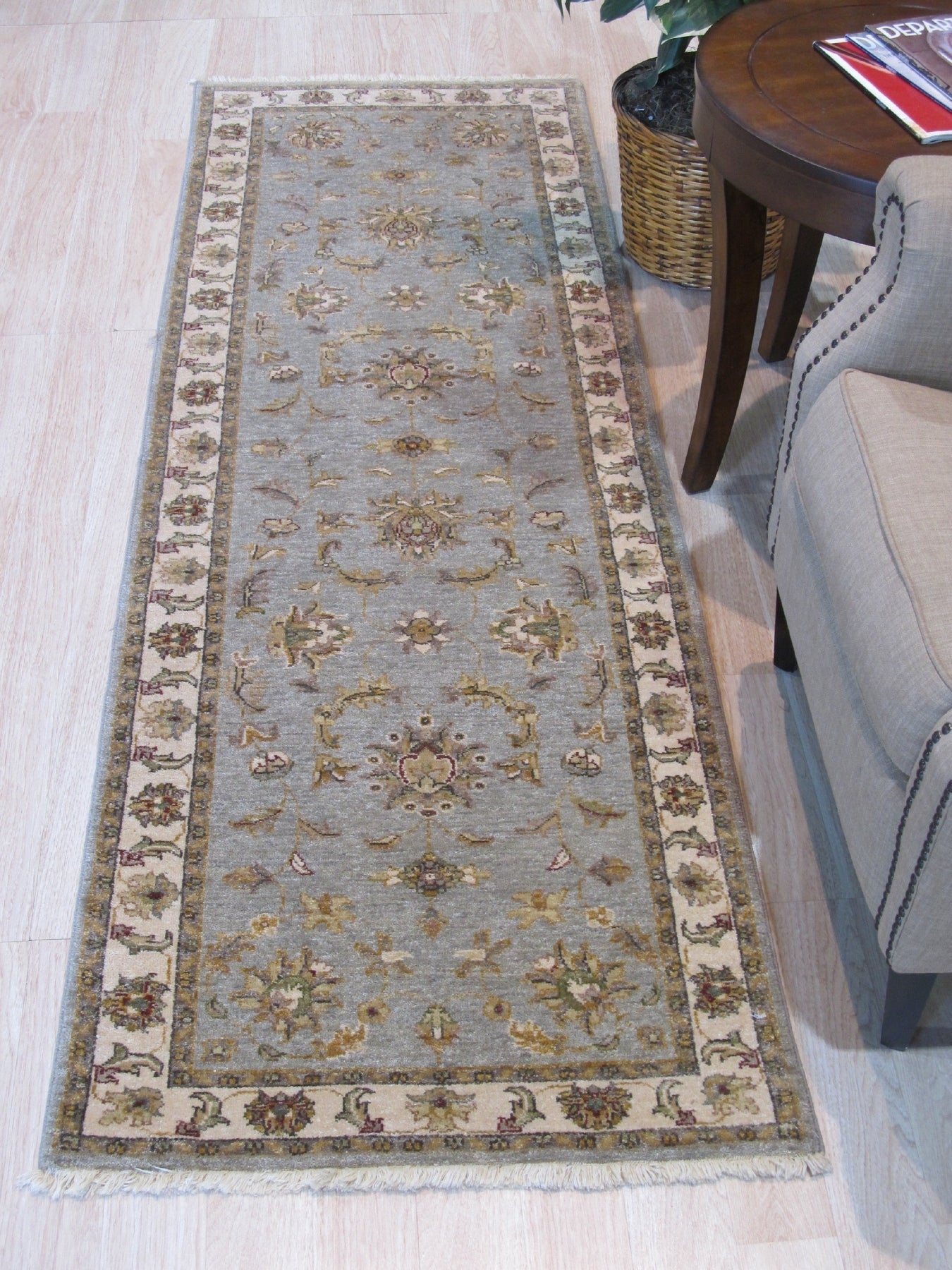 Zinnia Agra Green Hand Knotted Wool Rug graces a brightly lit interior; intricate patterns dance across its green wool field, lending warmth and texture to the space.