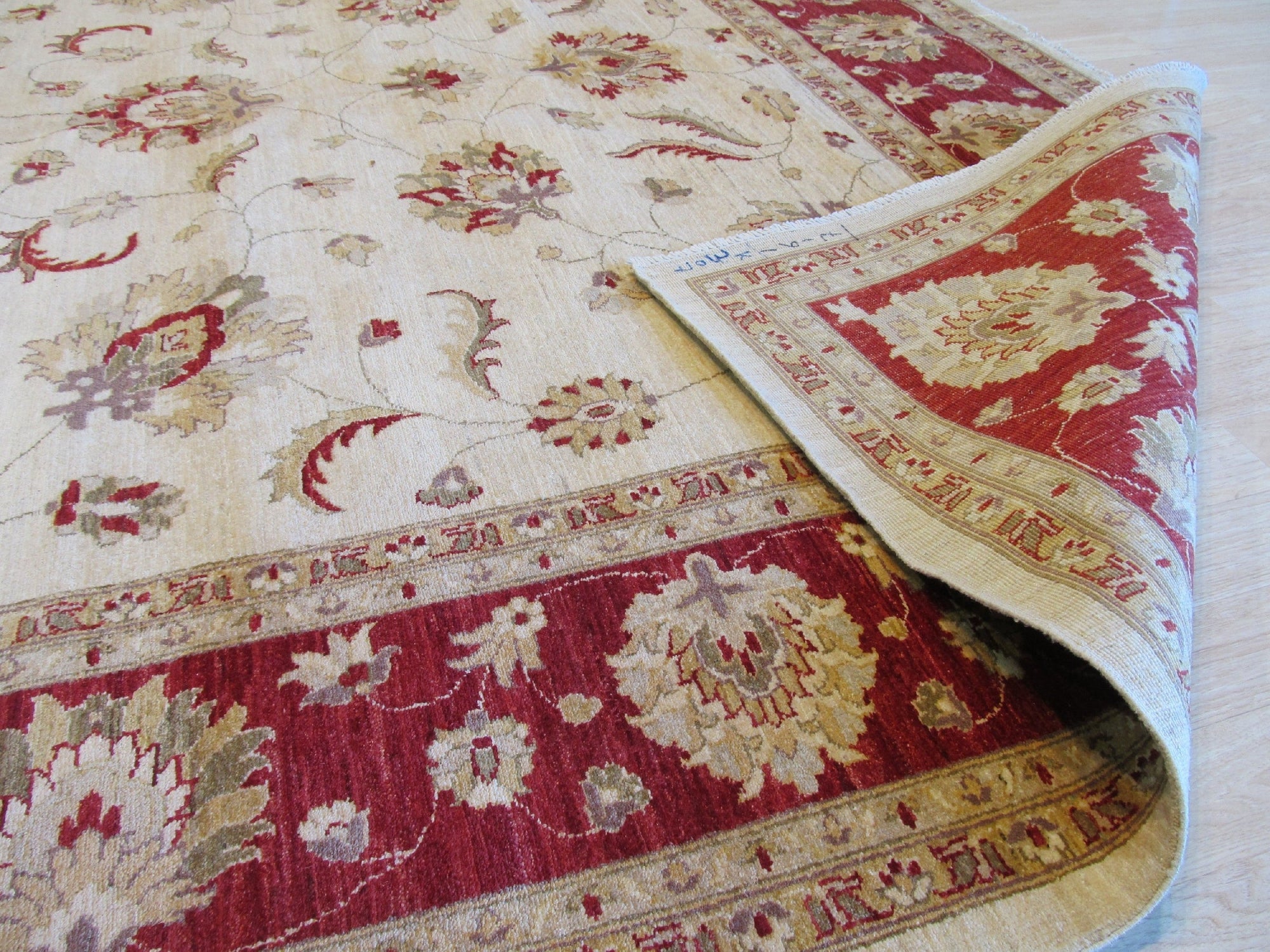 Para Peshawar Multicolor Hand Knotted Wool Rug, displaying vibrant geometric patterns in reds, blues, greens, and yellows, layered atop a dark wood floor in a contemporary living space.