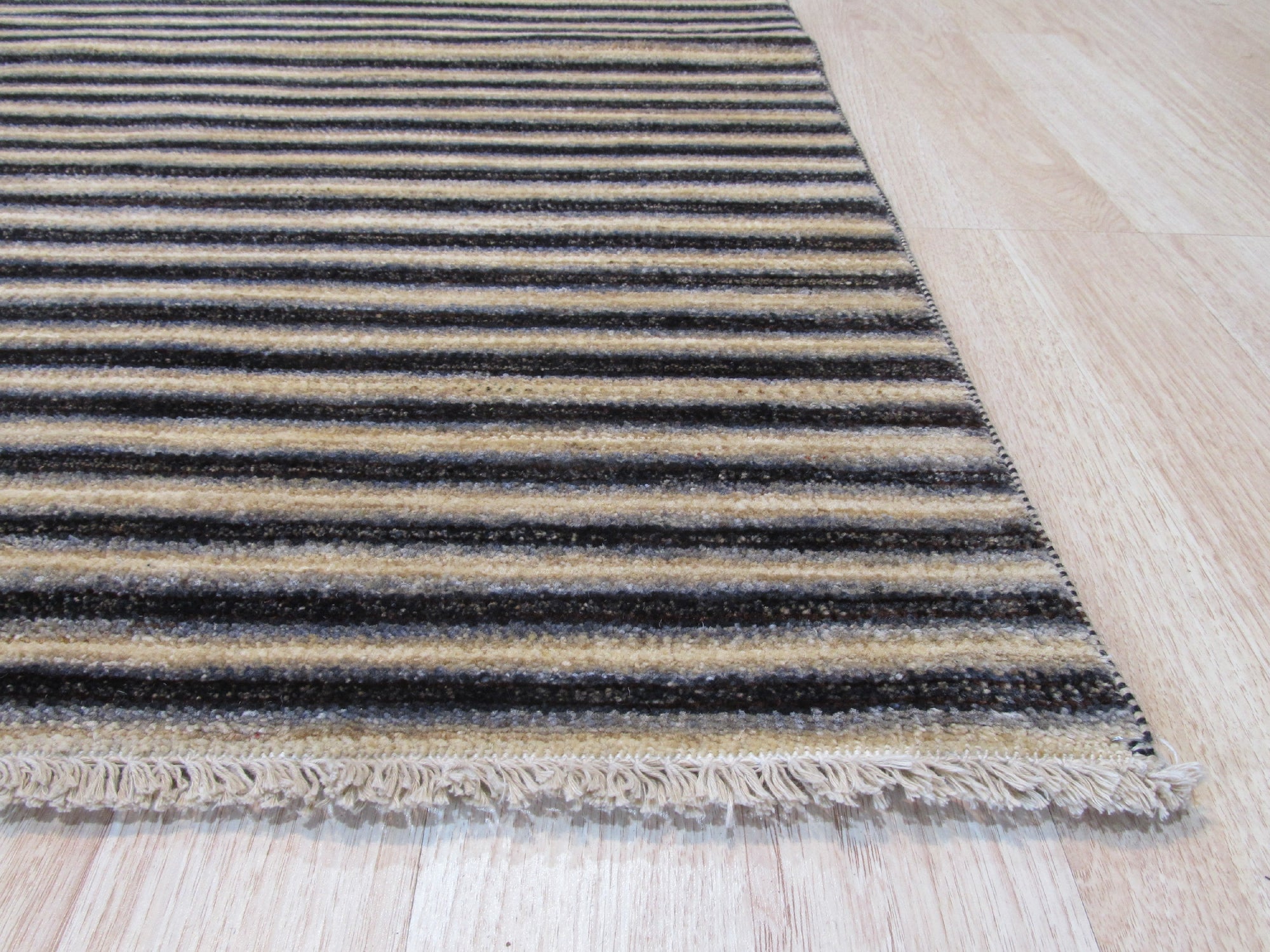 Isla Striped Multicolor Hand Knotted Wool Rug anchoring a bright living space. A medley of warm hues – terracotta, mustard, cream, and hints of teal – stripes across this hand-knotted wool rug, adding playful texture and vibrant energy to the room.