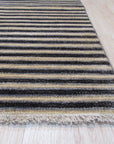 Isla Striped Multicolor Hand Knotted Wool Rug anchoring a bright living space. A medley of warm hues – terracotta, mustard, cream, and hints of teal – stripes across this hand-knotted wool rug, adding playful texture and vibrant energy to the room.
