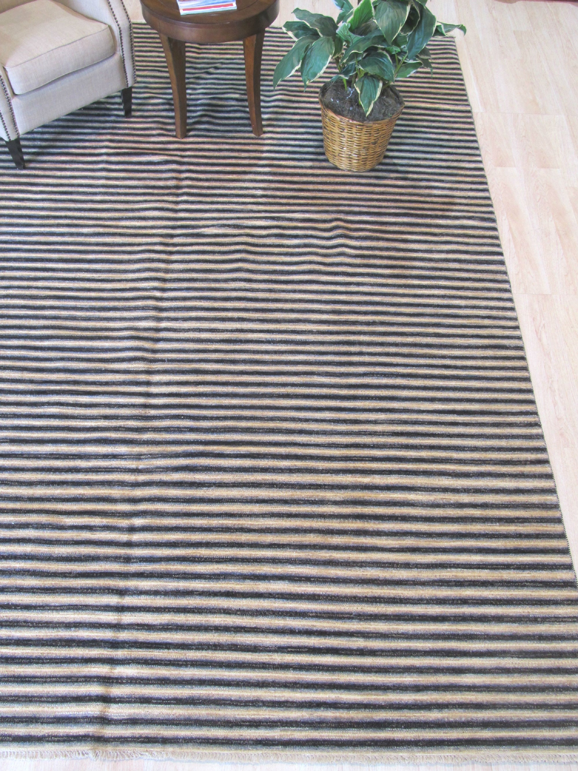Isla Striped Multicolor Hand Knotted Wool Rug graces a well-lit living room, its vibrant stripes of warm yellows, blues, reds, and greens adding playful energy to the space, showcasing the hand-knotted texture and wool's soft pile.