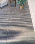 Isla Striped Multicolor Hand Knotted Wool Rug graces a well-lit living room, its vibrant stripes of warm yellows, blues, reds, and greens adding playful energy to the space, showcasing the hand-knotted texture and wool's soft pile.