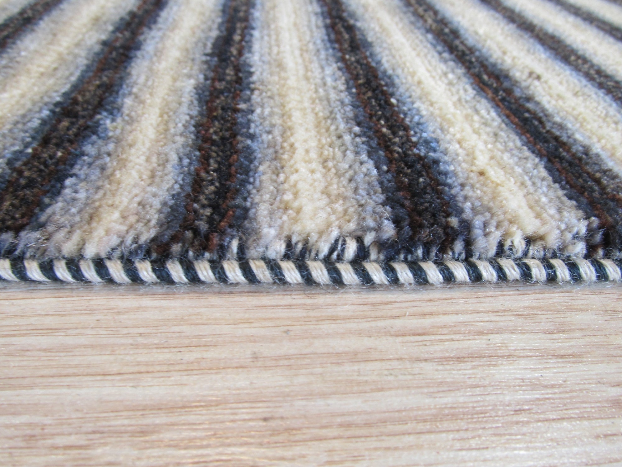 Isla Striped Multicolor Hand Knotted Wool Rug, its vibrant bands of color adding warmth and texture to a neutral living space, hints of blues, reds, and yellows dancing across the hand-knotted wool.