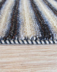 Isla Striped Multicolor Hand Knotted Wool Rug, its vibrant bands of color adding warmth and texture to a neutral living space, hints of blues, reds, and yellows dancing across the hand-knotted wool.