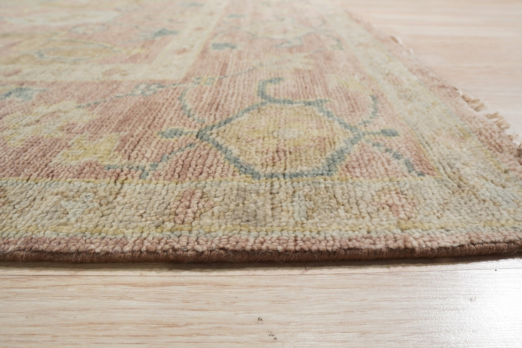 Timeless Oushak Pink Hand Knotted Wool Rug, its soft pink hues and intricate Oushak patterns accentuating a living room space with warm, inviting textures and natural light.