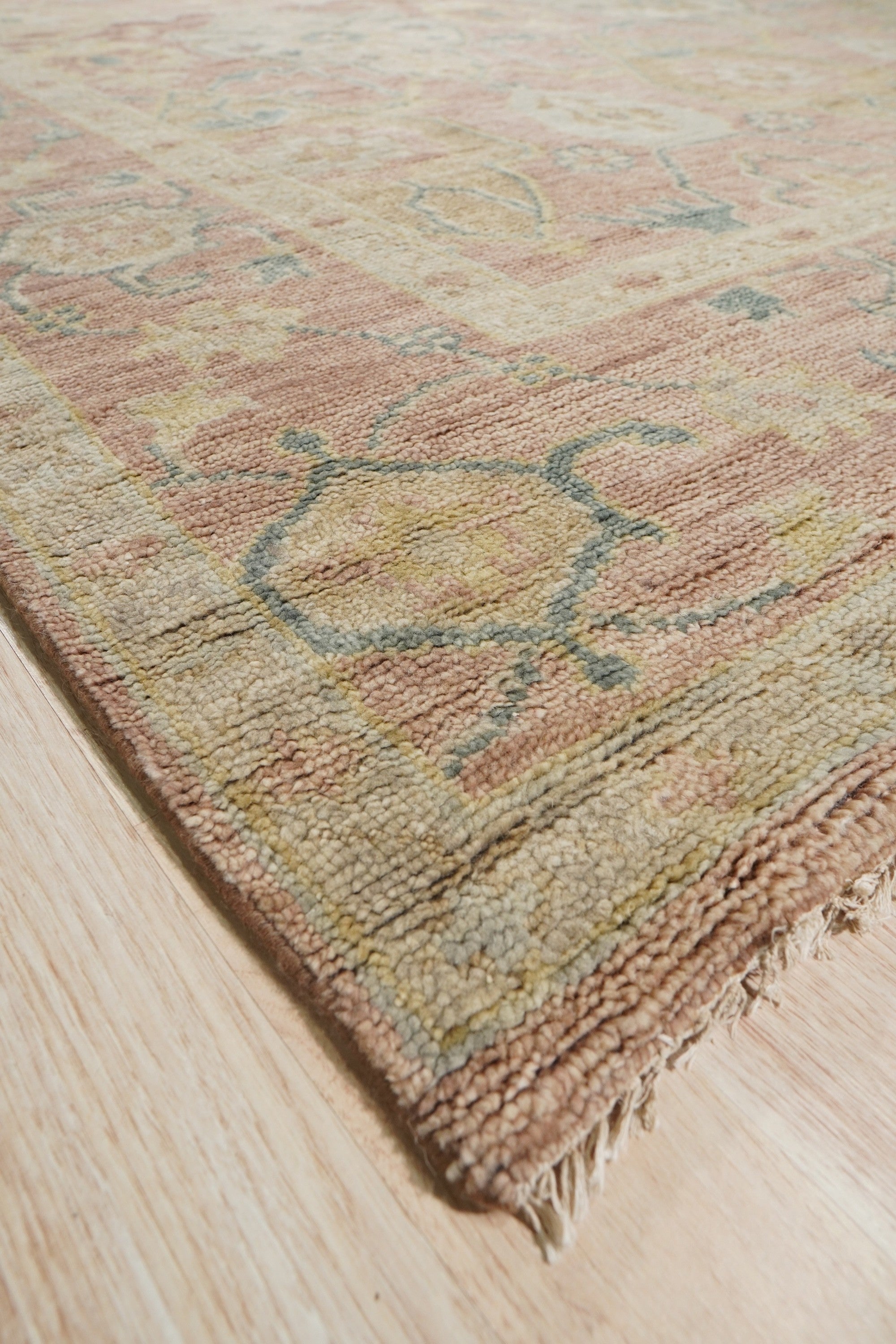 Timeless Oushak Pink Hand Knotted Wool Rug, soft blush hues and intricate floral motifs dance across this hand-knotted wool rug, lending an elegant and inviting warmth to a bright living space.