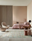 Timeless Oushak Pink Hand Knotted Wool Rug, displaying a delicate floral pattern in muted pink and beige tones, rests on a hardwood floor, creating a warm and inviting ambiance.