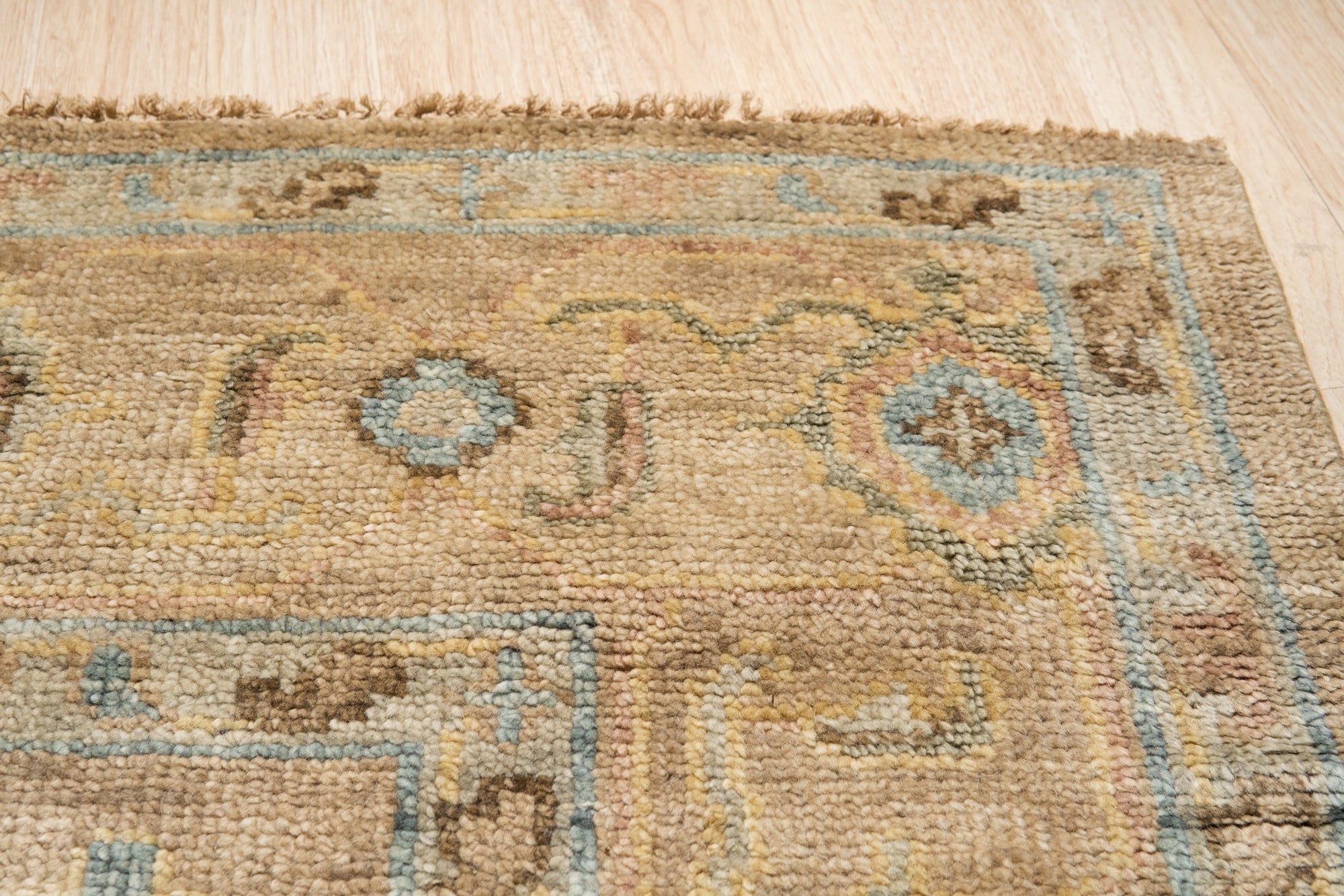 Captivating Traditional Beige Hand Knotted Wool Rug, a soft beige wool rug with intricate traditional patterns, resting on a hardwood floor and partially obscured by a mid-century modern style wooden chair.