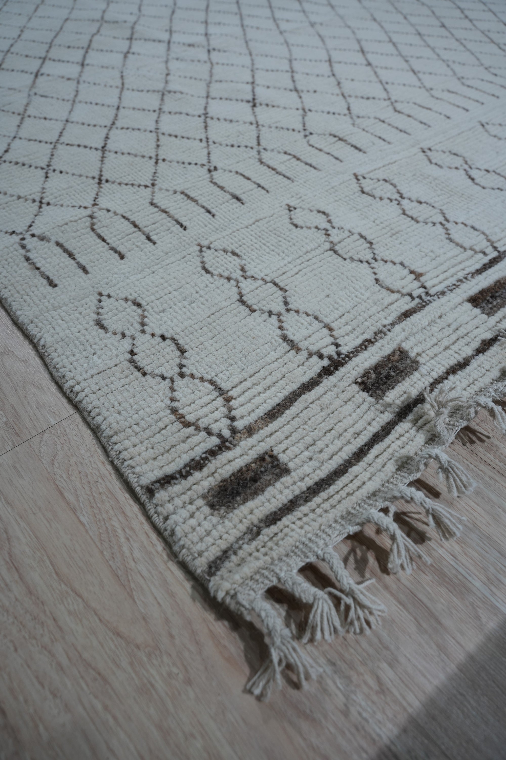 Jasmine Moroccan Ivory Hand Knotted Wool Rug, its plush ivory wool pile displaying a subtle geometric Moroccan pattern, rests serenely in a bright, airy living space.