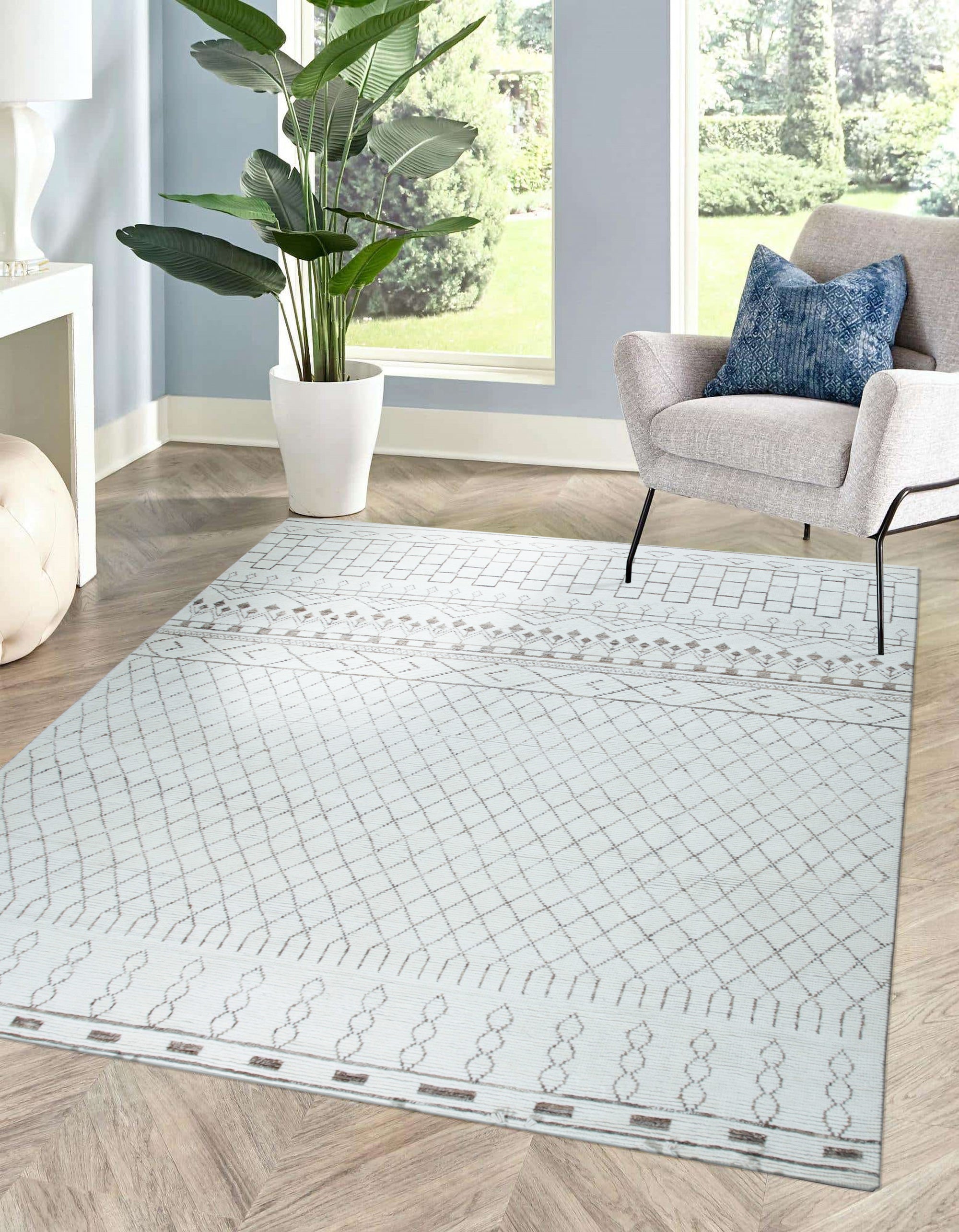 Jasmine Moroccan Ivory Hand Knotted Wool Rug displayed on a light hardwood floor. Intricate geometric patterns in raised ivory wool create a plush texture. Subtle variations in the ivory hue add depth and character to the hand-knotted design.