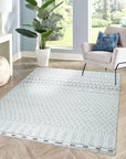 Jasmine Moroccan Ivory Hand Knotted Wool Rug displayed on a light hardwood floor. Intricate geometric patterns in raised ivory wool create a plush texture. Subtle variations in the ivory hue add depth and character to the hand-knotted design.