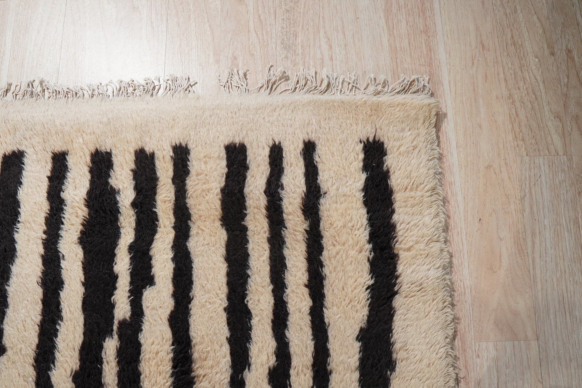 Mira Iris Yellow Hand Knotted Wool Rug, displaying a vibrant pattern with shades of yellow and other subtle hues, resting on a dark hardwood floor, creating a warm and inviting ambiance in a well-lit interior.
