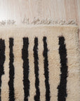Mira Iris Yellow Hand Knotted Wool Rug, displaying a vibrant pattern with shades of yellow and other subtle hues, resting on a dark hardwood floor, creating a warm and inviting ambiance in a well-lit interior.