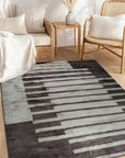 Nadia Mira Brown Hand Knotted Wool Rug displayed in a warmly lit room, its intricate brown and cream patterns complementing the neutral decor.