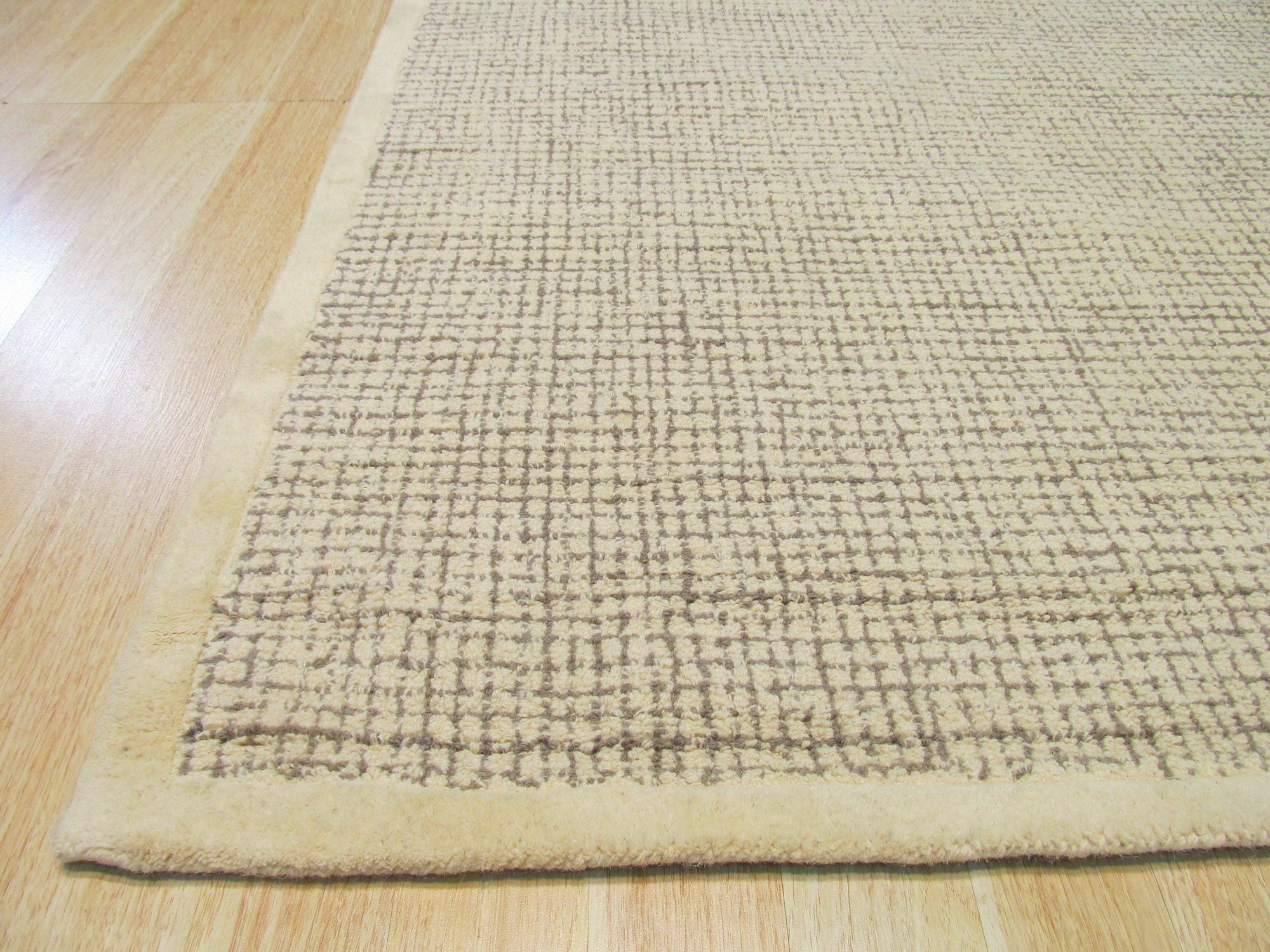 Quinn Artisan Ivory Hand Tufted Wool Rug graces a modern living room; its plush, ivory wool contrasting beautifully with the dark hardwood floors and complementing the minimalist furniture.