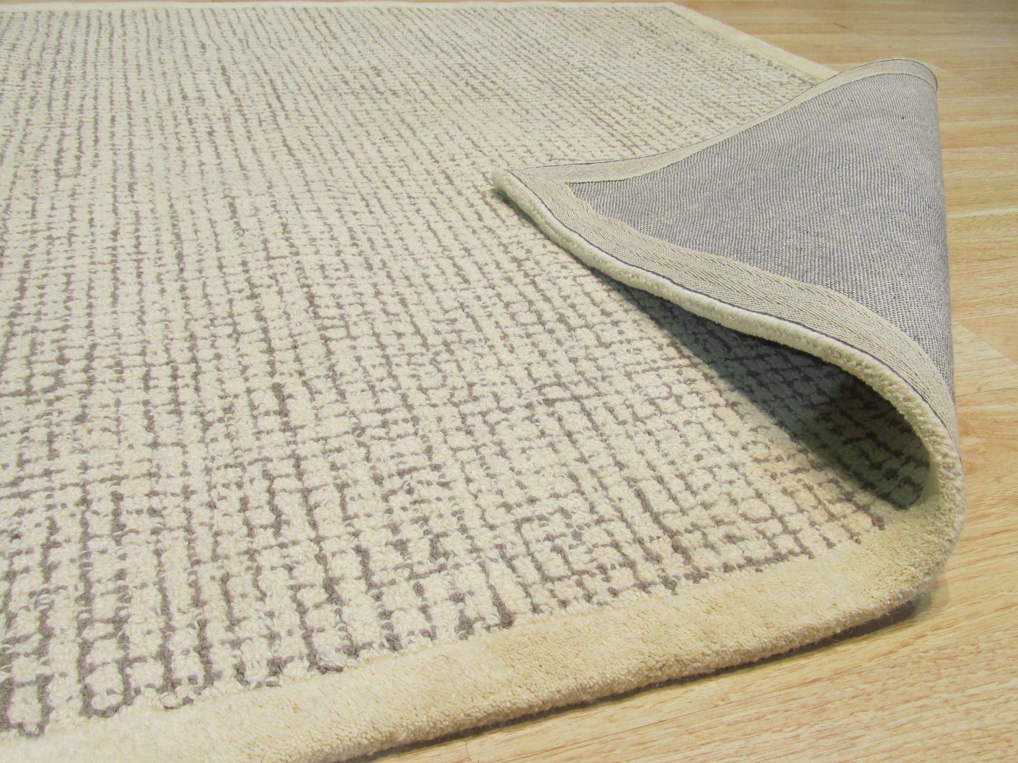 Quinn Artisan Ivory Hand Tufted Wool Rug, its thick, plush ivory wool pile inviting touch, showcased within a bright, airy living space.