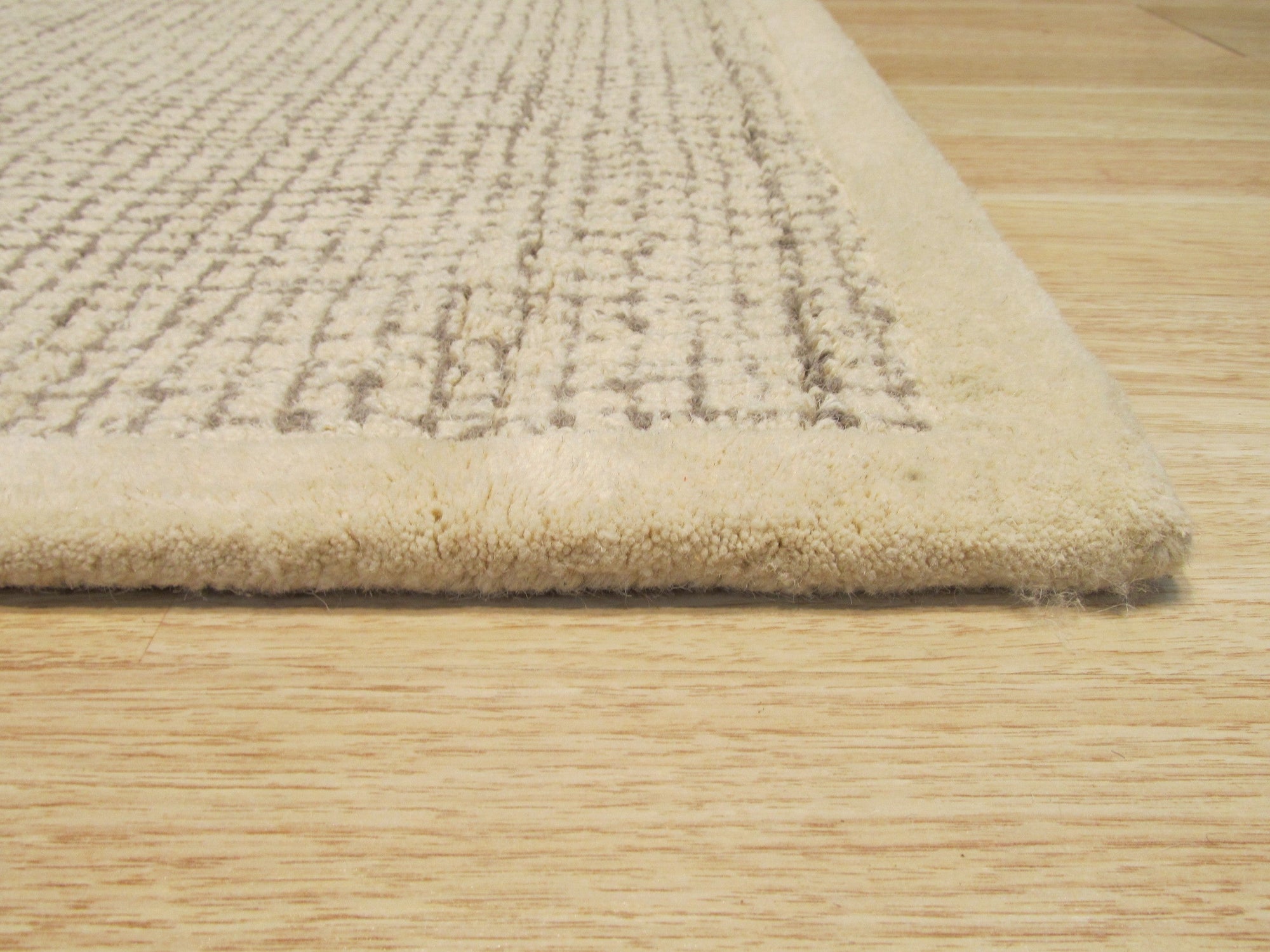 Quinn Artisan Ivory Hand Tufted Wool Rug, a textured expanse of soft ivory wool, hand tufted for a luxurious feel, graces a stylish living space.
