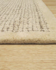 Quinn Artisan Ivory Hand Tufted Wool Rug, a textured expanse of soft ivory wool, hand tufted for a luxurious feel, graces a stylish living space.