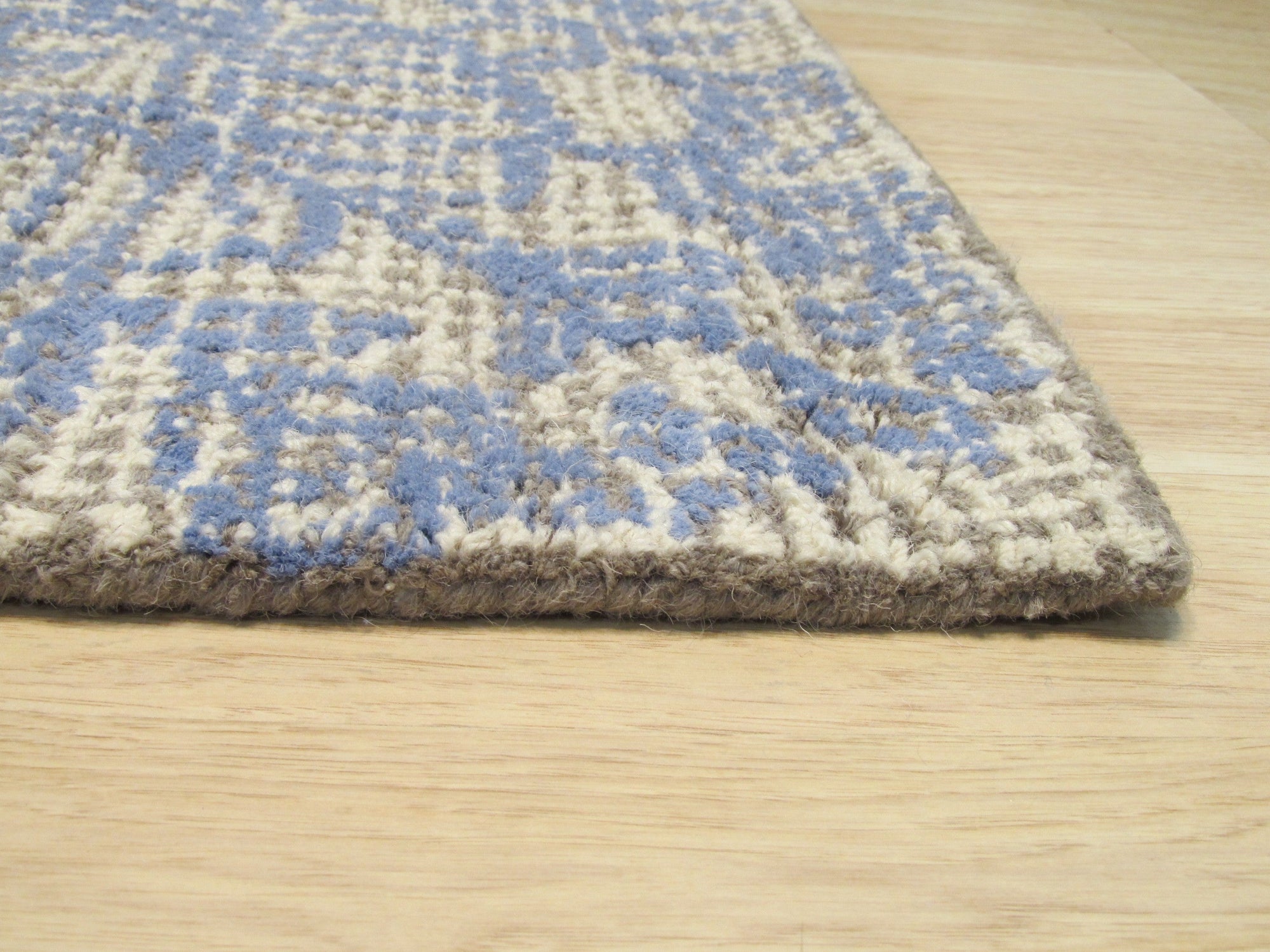 Rustic Stylish Beige Hand Tufted Wool Rug, showcasing its textured wool construction in a warm beige hue, partially visible beneath furniture legs in a styled living room setting.