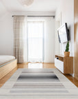 Classic Artistic Gray Flatweave Wool & Viscose Rug, a textured gray foundation with subtle, artistic striations, lays flat against a light hardwood floor, its wool and viscose blend catching the sunlight to reveal soft variations in tone.