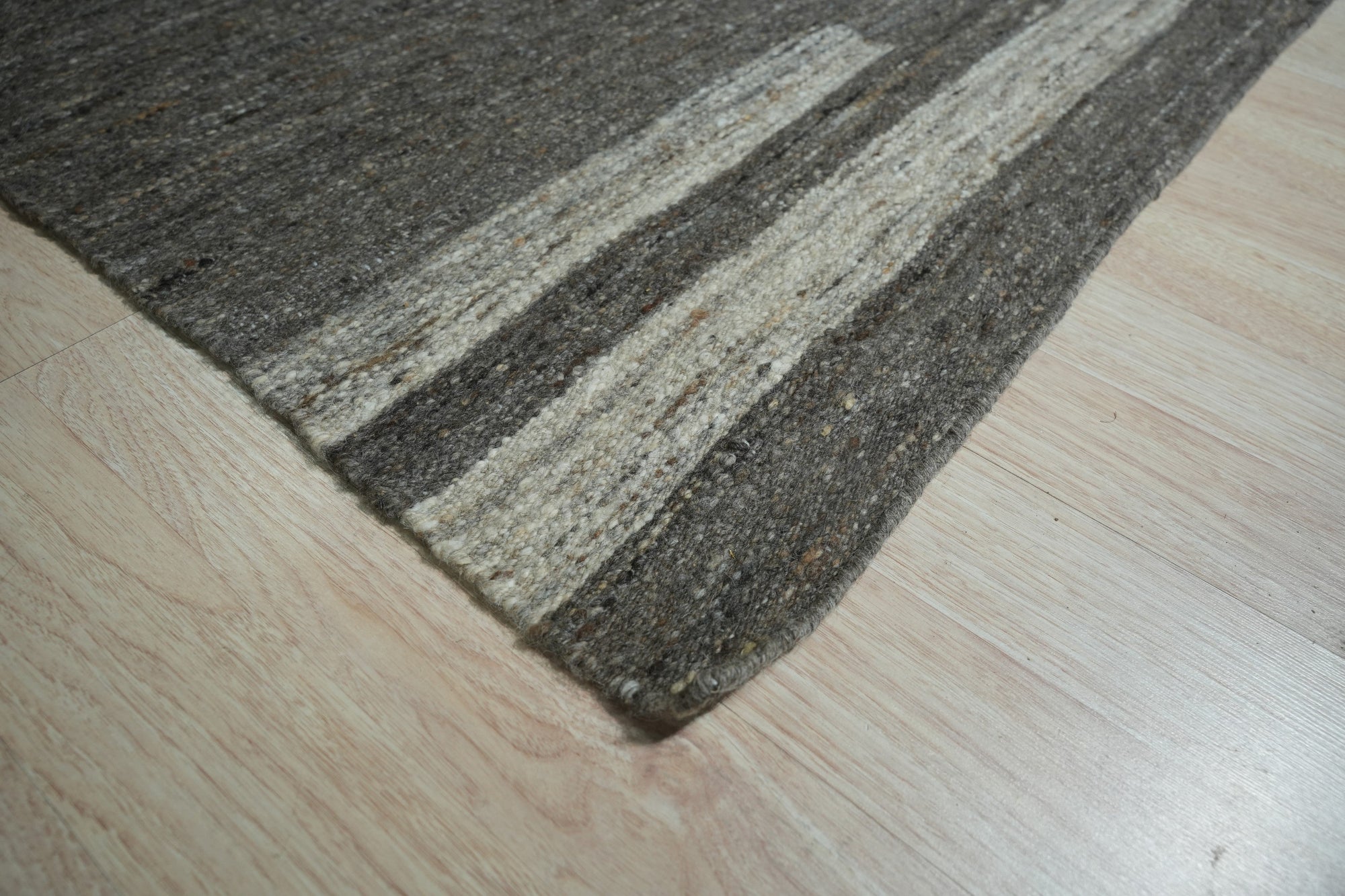Cassandra Clara Brown Flatweave Wool Rug, its geometric pattern in shades of brown and cream grounding a light-filled living room with modern furniture.