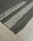 Cassandra Clara Brown Flatweave Wool Rug, its geometric pattern in shades of brown and cream grounding a light-filled living room with modern furniture.