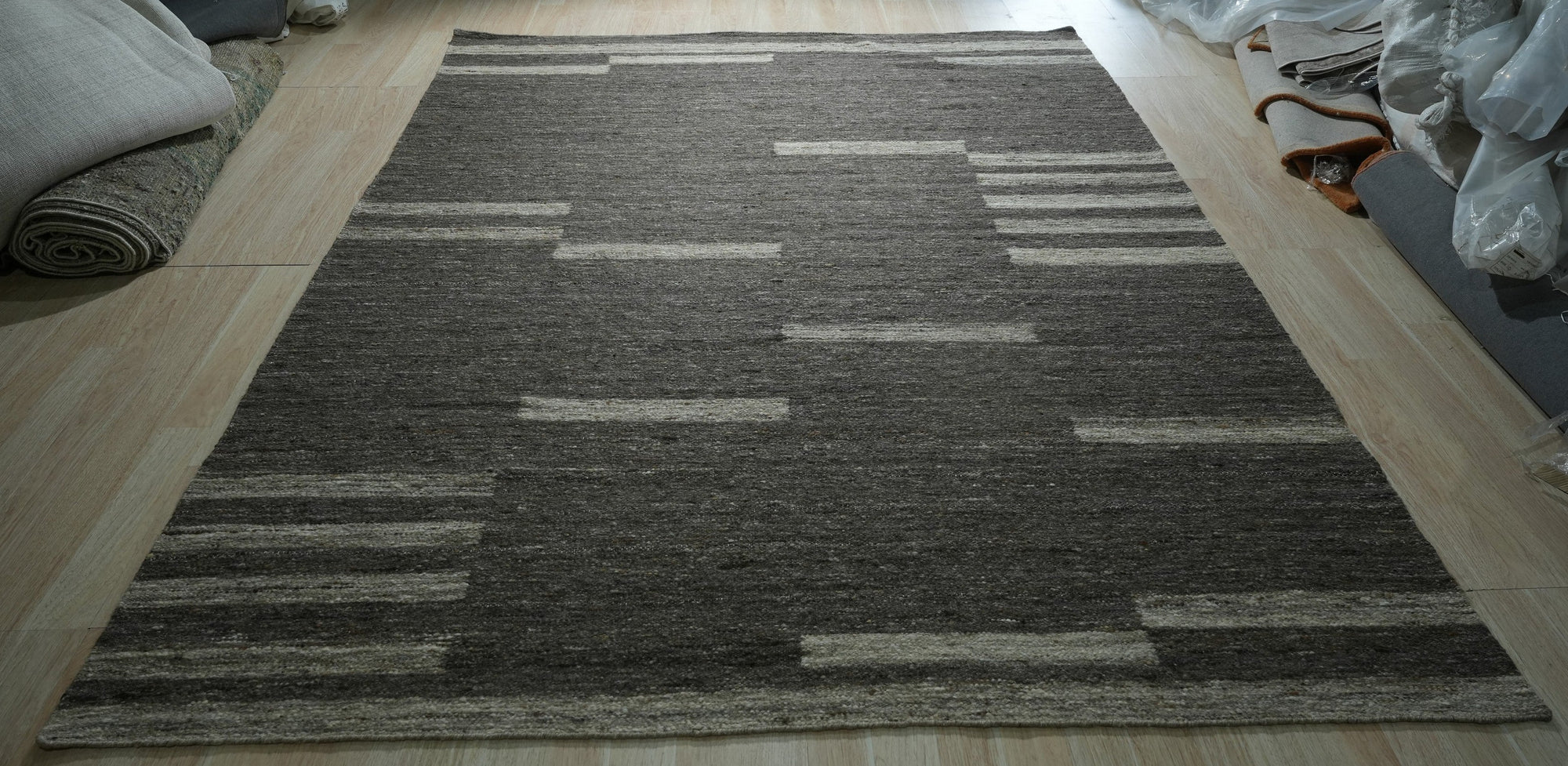 Cassandra Clara Brown Flatweave Wool Rug, a rich brown wool flatweave, displayed in a bright, modern living room with light wood floors.