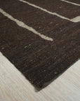 Talia Delicate Brown Flatweave Wool Rug, a brown flatweave wool rug with a subtle, textured pattern, seen in a bright living space, partially covered by a modern coffee table.