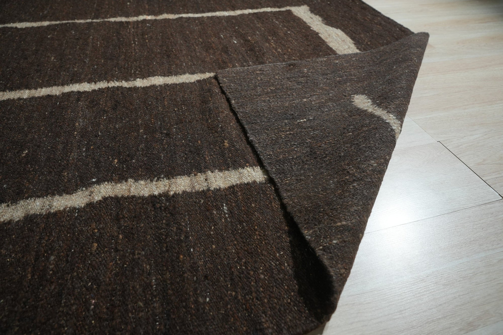 Talia Delicate Brown Flatweave Wool Rug, its subtle, interwoven texture adding warmth to a modern living space with neutral-toned furniture and natural light.