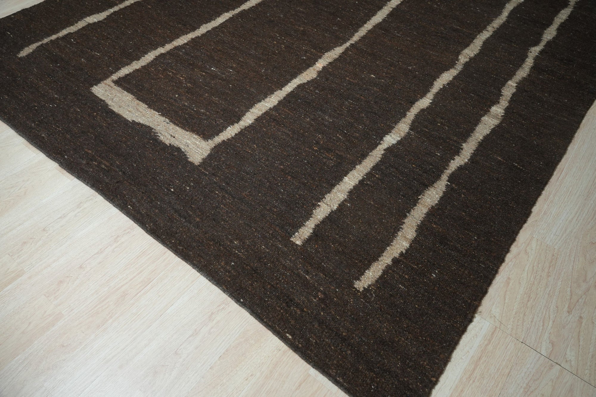 Talia Delicate Brown Flatweave Wool Rug, showcasing its subtle pattern and warm brown hues in a bright, airy living space. Flatweave construction highlights the rug's texture and understated elegance.