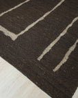 Talia Delicate Brown Flatweave Wool Rug, showcasing its subtle pattern and warm brown hues in a bright, airy living space. Flatweave construction highlights the rug's texture and understated elegance.