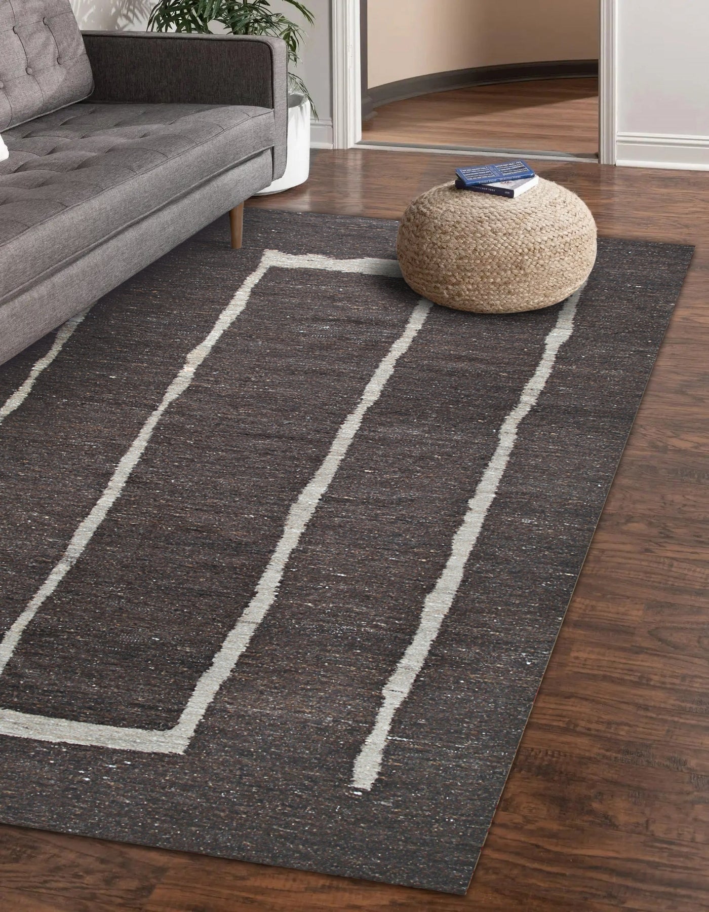 Talia Delicate Brown Flatweave Wool Rug gracing a light-filled living room. Warm brown tones and flatweave texture complement the neutral décor. Wool construction visible in the rug's subtle pattern.