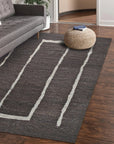 Talia Delicate Brown Flatweave Wool Rug gracing a light-filled living room. Warm brown tones and flatweave texture complement the neutral décor. Wool construction visible in the rug's subtle pattern.