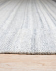 Clara Unique Gray Flatweave Wool & Viscose Rug, showcasing a subtle geometric pattern in shades of gray, blends seamlessly into a bright, modern living room setting.