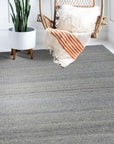 Clara Unique Gray Flatweave Wool & Viscose Rug, displayed in a modern living room, its subtle gray tones complementing light wood furniture and a neutral color palette.