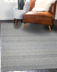 Clara Unique Gray Flatweave Wool & Viscose Rug, showcasing a subtle, textured gray surface with light variations, lending a sophisticated and modern feel to a brightly lit living space.